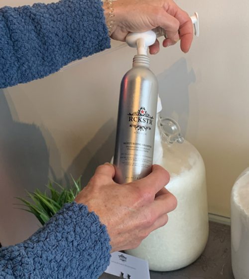 Woman refilling a RCKSTR shampoo bottle